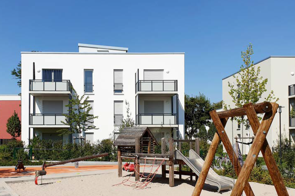 Mehrfamilienhaus mit Balkonen und Spielplatz im Vordergrund